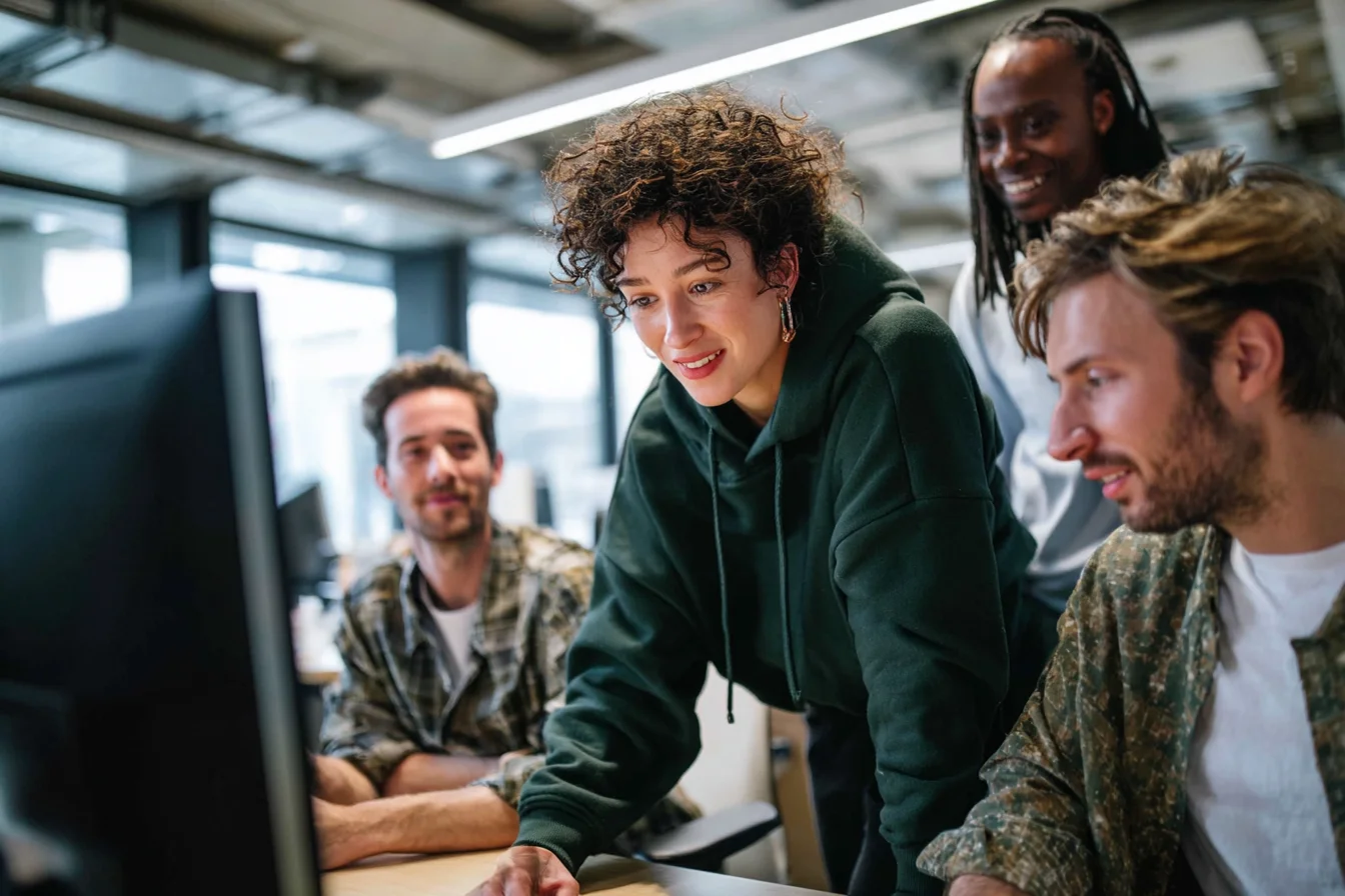 Ein Team von 4 Menschen sitzen vor einem Laptop